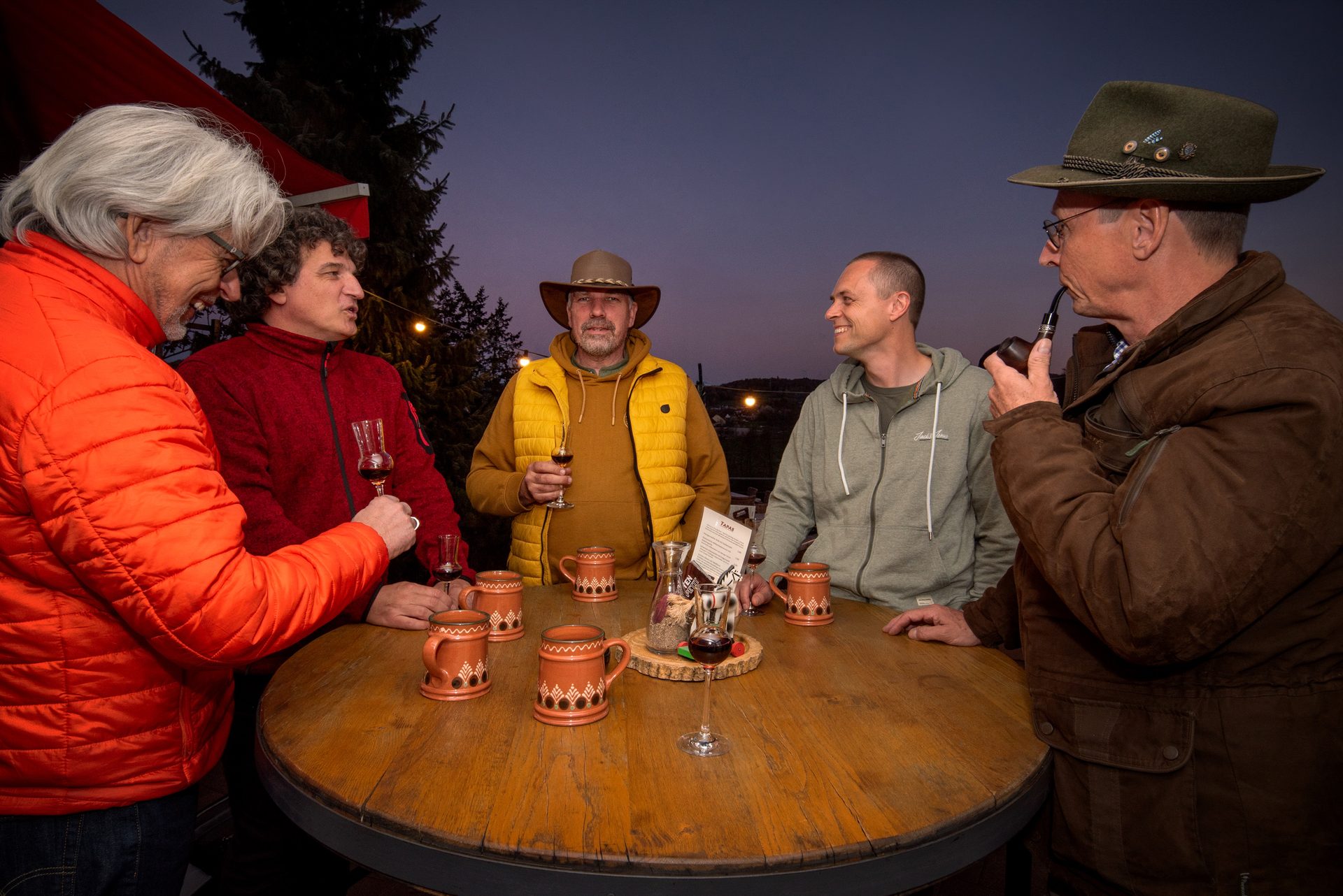 Männerrunde mit Steinkrügen in der Abenddämmerung